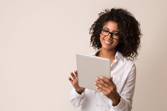 Happy businesswoman using tablet over light background