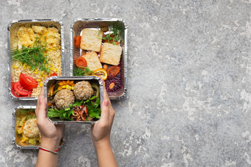 Foil containers with delicious food on gray background