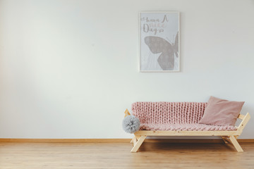 Real photo of bright room interior for kid with wooden sofa with pastel pink blanket, cushion and...