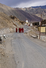 Young monks in red robes walking on Himalayan road, Ladakh, India