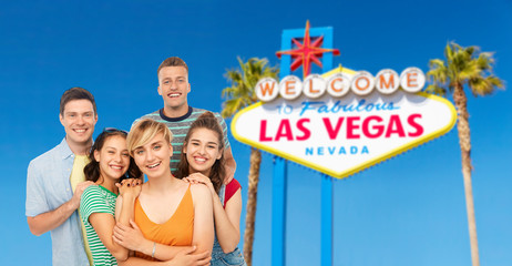 travel, tourism and vacation concept - group of happy smiling friends over welcome to fabulous las vegas sign background