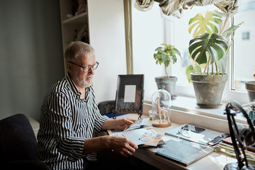 happy mature man looking his old wedding photos while sitting in home