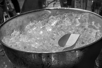 Ice bucket full with crushed ice from top view or from above including clipping path Scoop in a large ice-filled bucket with blurred wine battles in the background.Catering set-up ready for the event 
