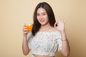 Young Asian woman drink orange juice show OK sign.