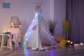 Cozy play tent for kids with glowing garland in room interior © Pixel-Shot