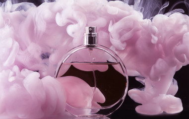 Bottle of perfume in color smoke on dark background