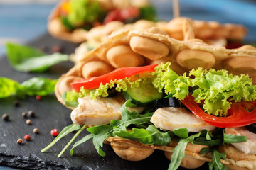 Delicious bubble waffle on slate plate with meat and vegetables, closeup