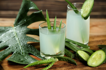 Glasses of fresh aloe vera juice with cucumber on wooden board