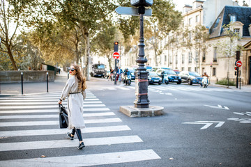 Cityscape view with woman crossing the street during the morning light in Paris, France