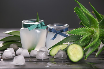Glass jars with fresh aloe vera juice on wooden table