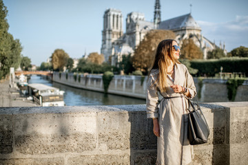 Lifestyle portrait of a young woman walking on the bridge with famous cathedral on the background in Paris, France