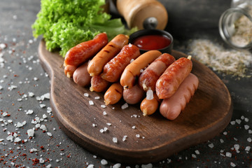 Delicious grilled sausages with salt on wooden board