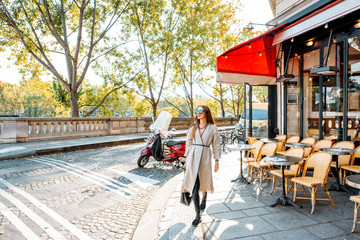 Street view with traditional french cafe and woman walking during the morning in Paris