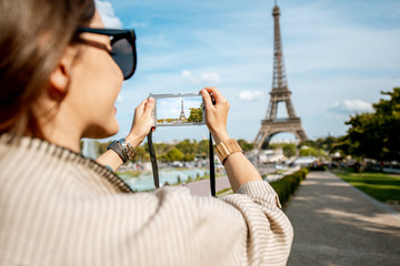 Woman tourist photographing with photocamera Eiffel tower while traveling in Paris