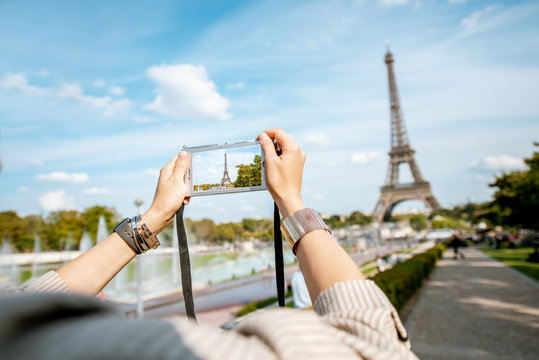 Woman tourist photographing with photocamera Eiffel tower while traveling in Paris. Cropped image with no face