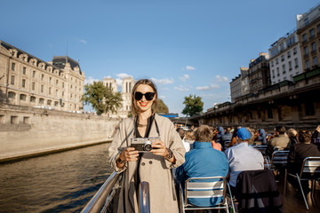 Young woman enjoying beautiful landscape view on the riverside from the tourist ship during the...