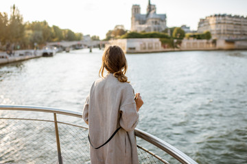 Young woman tourist enjoying beautiful landscape view on the riverside with Notre-Dame cathedral...