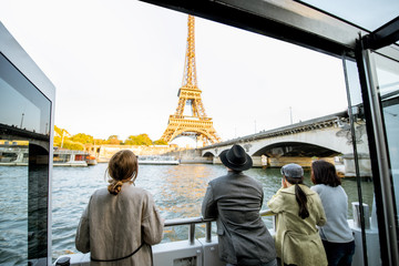 People enjoying beautiful landscape view on the riverside with Eiffel tower from the boat during the sunset in Paris