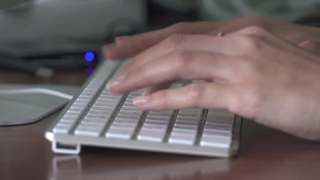 Woman's hands typing on computer keyboard close up
