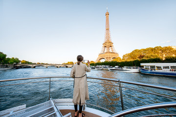Young woman enjoying beautiful landscape view on the riverside with Eiffel tower from the boat...