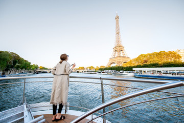 Young woman enjoying beautiful landscape view on the riverside with Eiffel tower from the boat...
