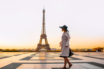 Woman dressed in coat and hat walking on the famous square with great view on the Eiffel tower early in the morning in Paris