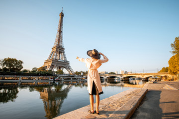 Young woman tourist enjoying landscape view on the Eiffel tower with beautiful reflection on the water during the mornign light in Paris - obrazy, fototapety, plakaty