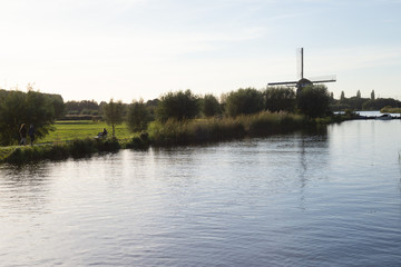 Part of the dike in the lake with windmill and the clouds in the background
