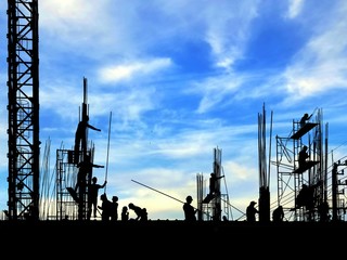 Silhouette construction workers group are working to build reinforcement structure on top of building with crane in construction site and blurred clouds with blue sky background, illustration mode
