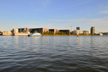 Obraz premium Rzeka Ij i budynki na brzegu w pogodny dzień.