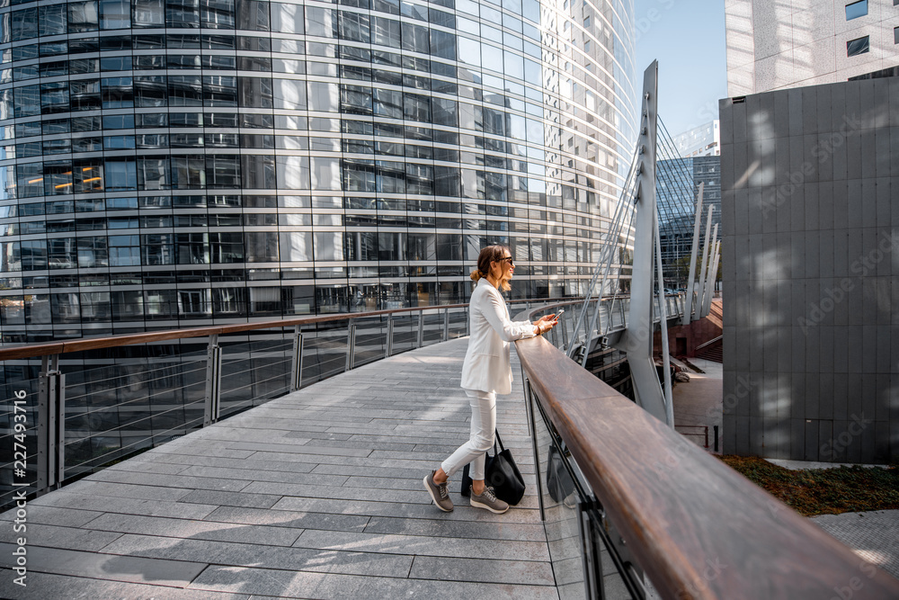 Wall mural business woman walking outdoors at the financial district with modern buildings on the background in