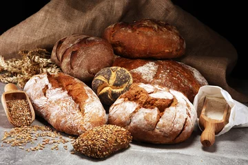 Different kinds of bread and bread rolls on board from above. Kitchen or bakery