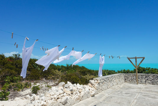 Clean white laundry dries on a clothesline with a blue sea in the background