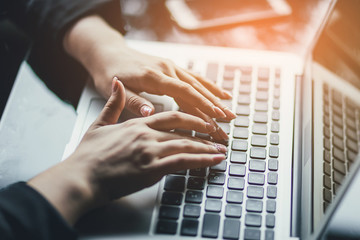 Womans hands using laptop in cafe. Sunshine background