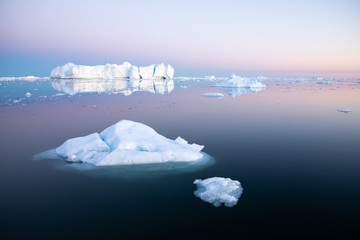 Early morning summer alpenglow lighting up icebergs during midnight season. Ilulissat, Greenland.