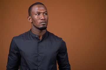 Fototapeta premium Portrait of handsome African businessman against brown background