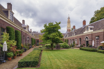 The almshouse the green garden in the old center of Haarlem with the tower of The Grote Kerk or Saint Bavokerk in the background