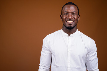Portrait of handsome African businessman against brown background