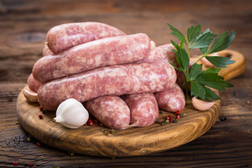 Raw sausages on the wooden board - obrazy, fototapety, plakaty