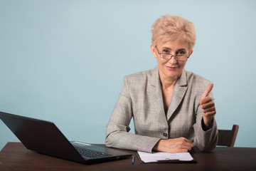 adult stylish attractive woman with short haircut in a suit at the table with a laptop