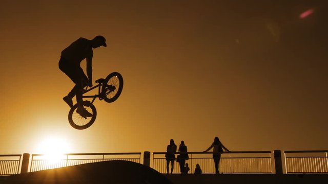 Young man doing ramp jump stunt on bmx bicycle on sunset slow motion