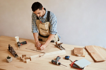 Woodmaker man making draft plan using pencil on the table with tools at furniture workshop