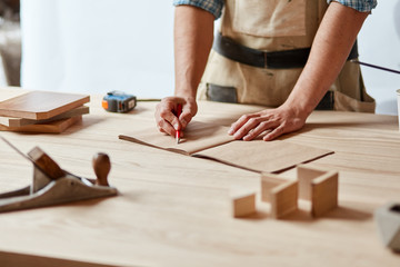 Close up of carpenter hands while working with his drawings and writing measuring in blank pocketbook, isolated against white wall