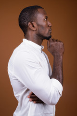 Portrait of handsome African businessman against brown background