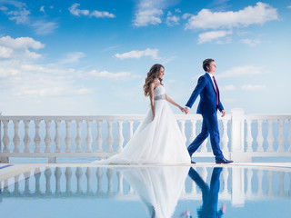 Happy wedding couple walking near pool outdoor. Bride and Groom together on their wedding day.