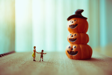 Miniature people, sister and brother standing with ghost pumpkin using as family and halloween concept