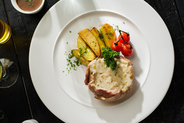 Pork with white mushroom sauce garnished with fried potatoes and cherry tomatoes. Top view