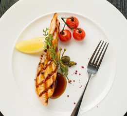 Grilled salmon steak with lemon and cherry tomatoes. View from above