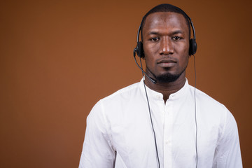 Handsome African businessman wearing headset against brown backg