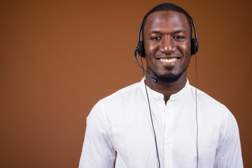 Handsome African businessman wearing headset against brown backg